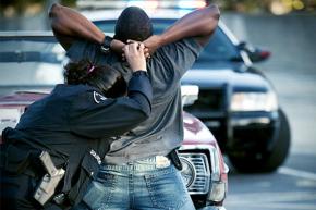 A New York City police officer searches a young Black man